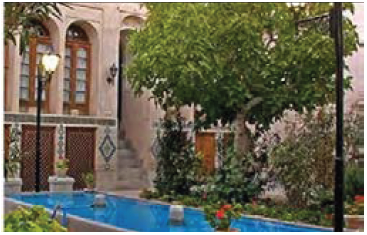 تصویری از حیاط سرسبز و حوض آب در میان آن
